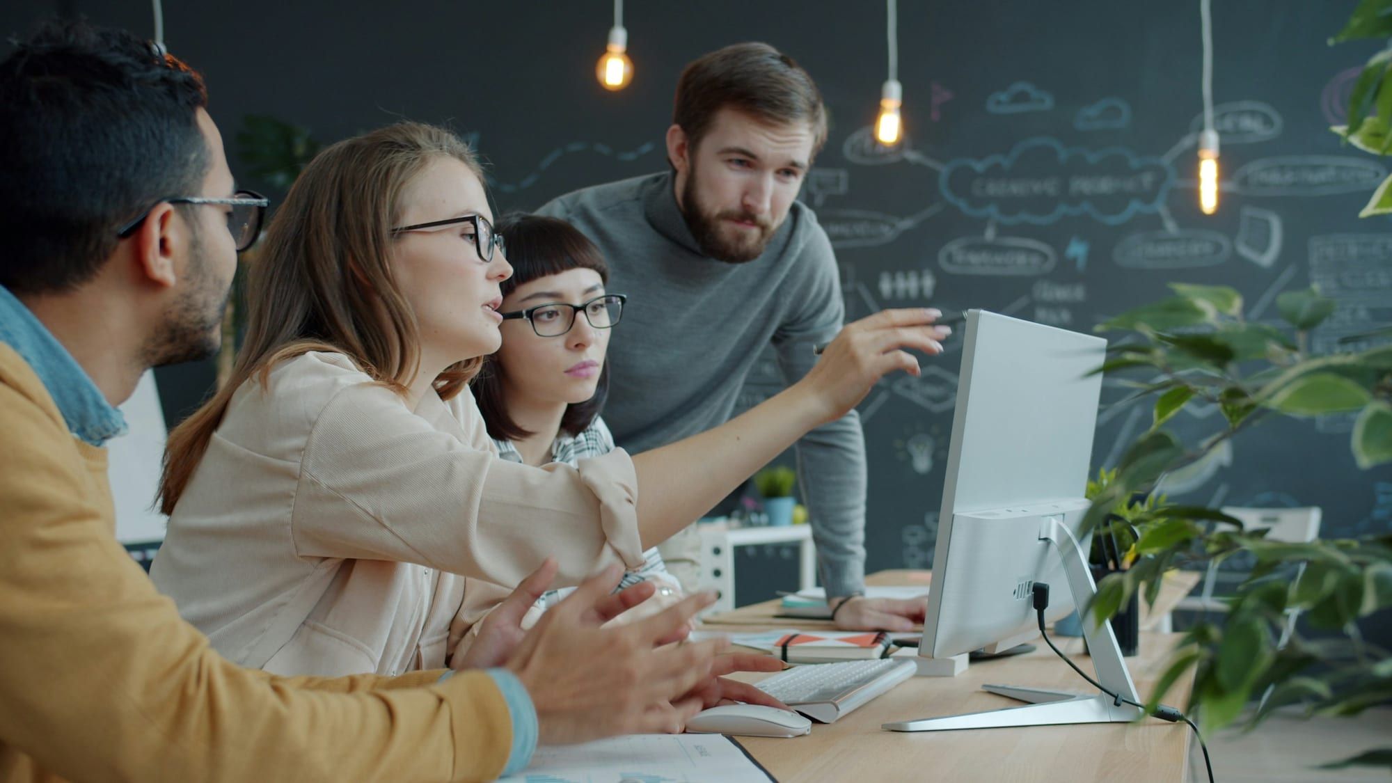 Colleagues gathered around a computer screen, discussing a project